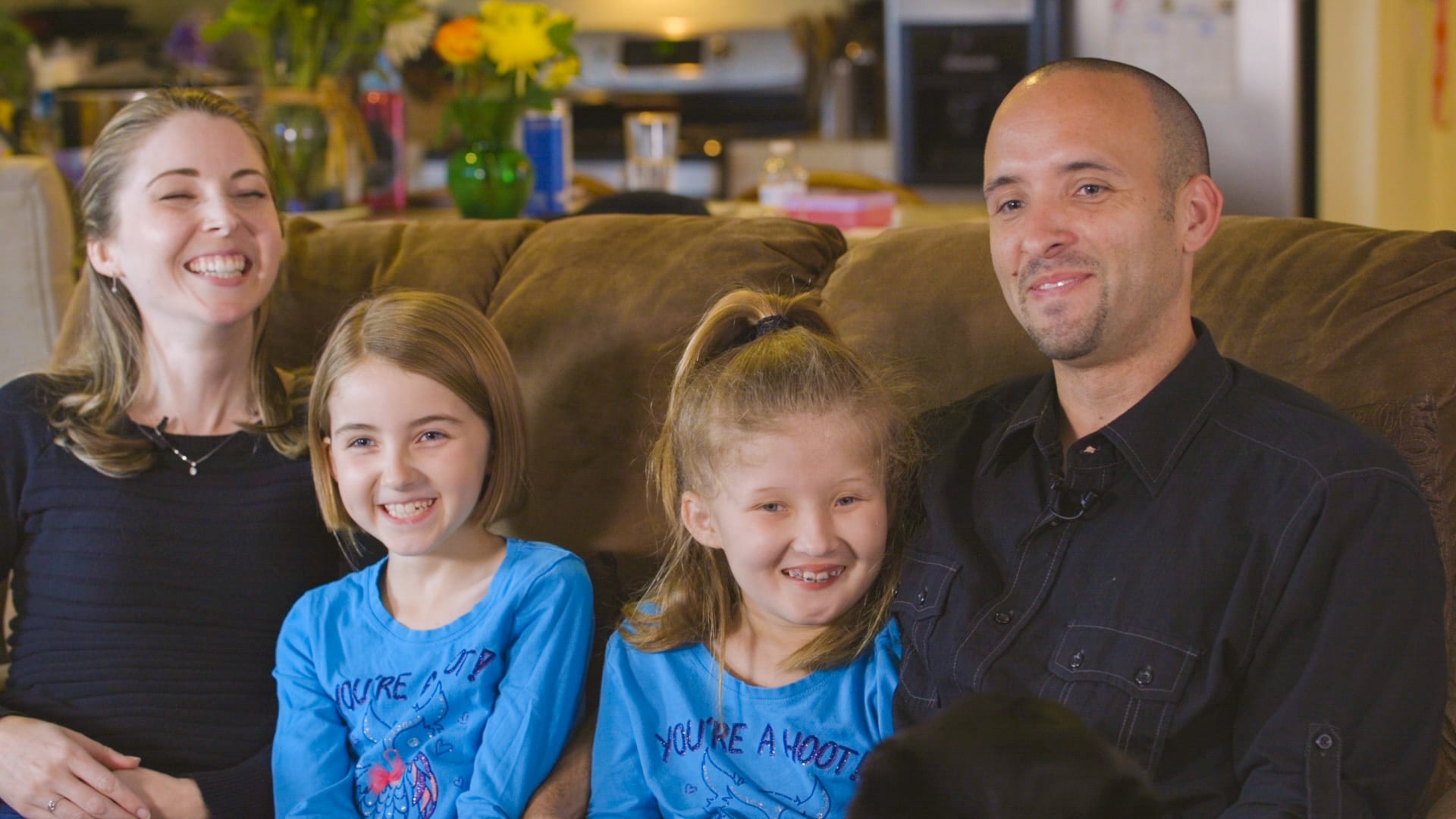 A mother, father and two daughters sitting on a couch. 