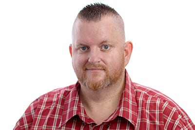 headshot of a brunette Caucasian male in a red and white plaid shirt against an all-white background